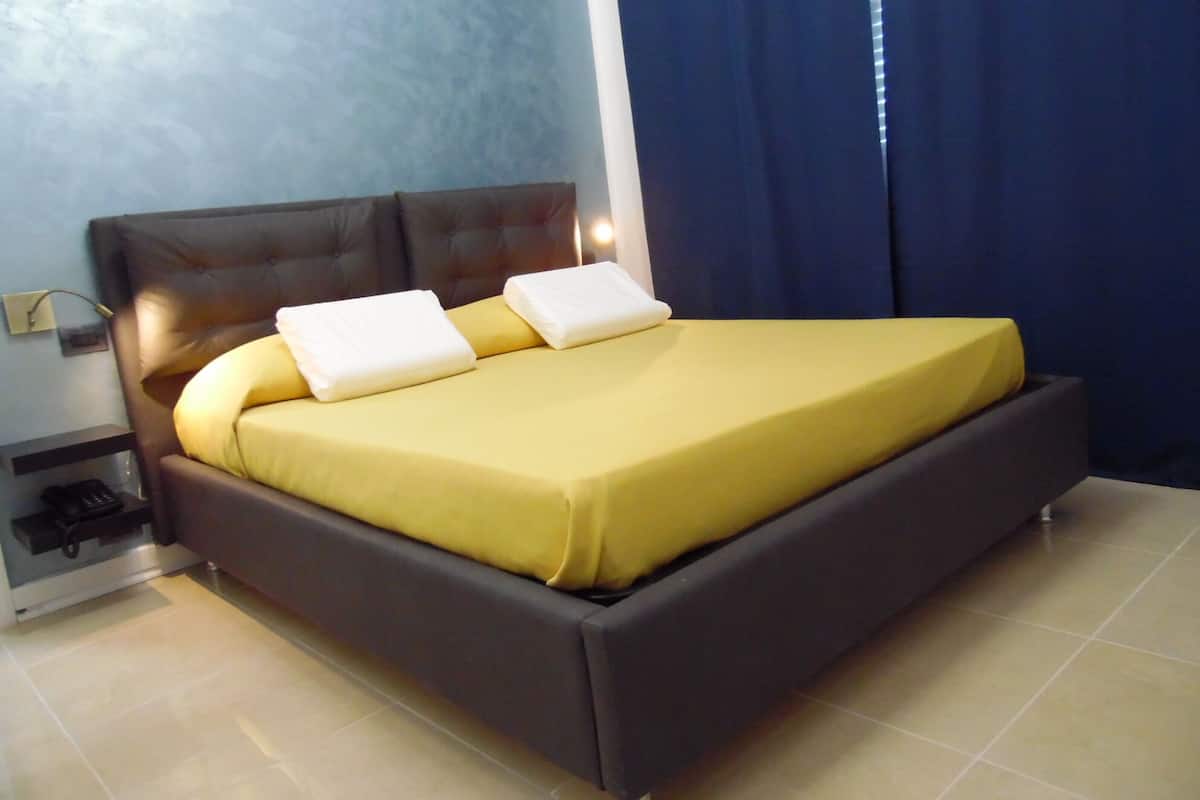 A bed with a dark headboard, a yellow bedspread, and two white pillows.