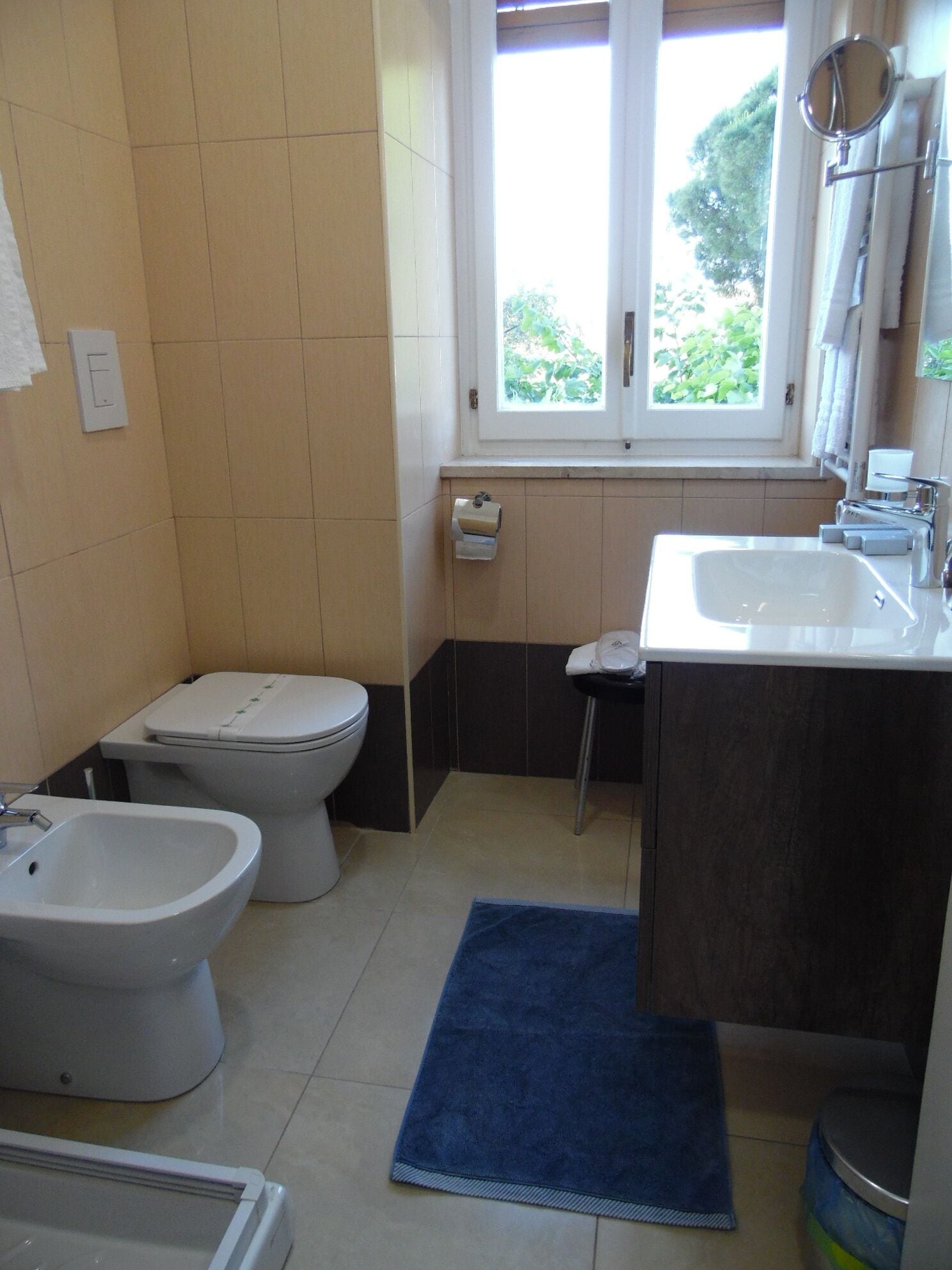 Ein Badezimmer mit Toilette, Bidet, Waschbecken und Fenster.
