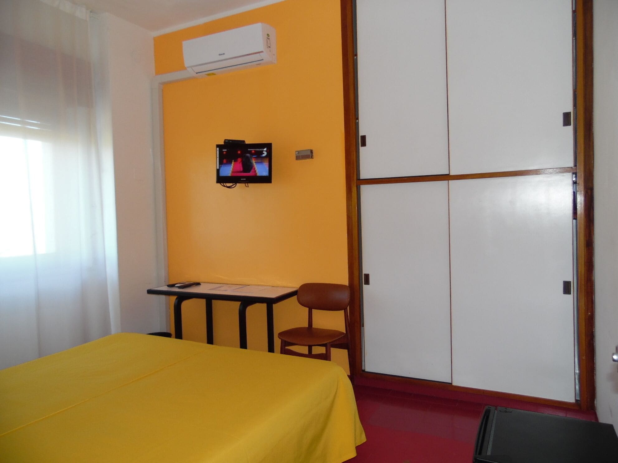 Una habitación con cama, escritorio, silla y armario.