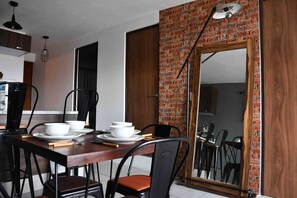 A dining area with a brick accent wall, a large mirror, and modern furniture. - Condo in Centro histórico de Guadalajara Downtown w/parking and pool (Guadalajara)