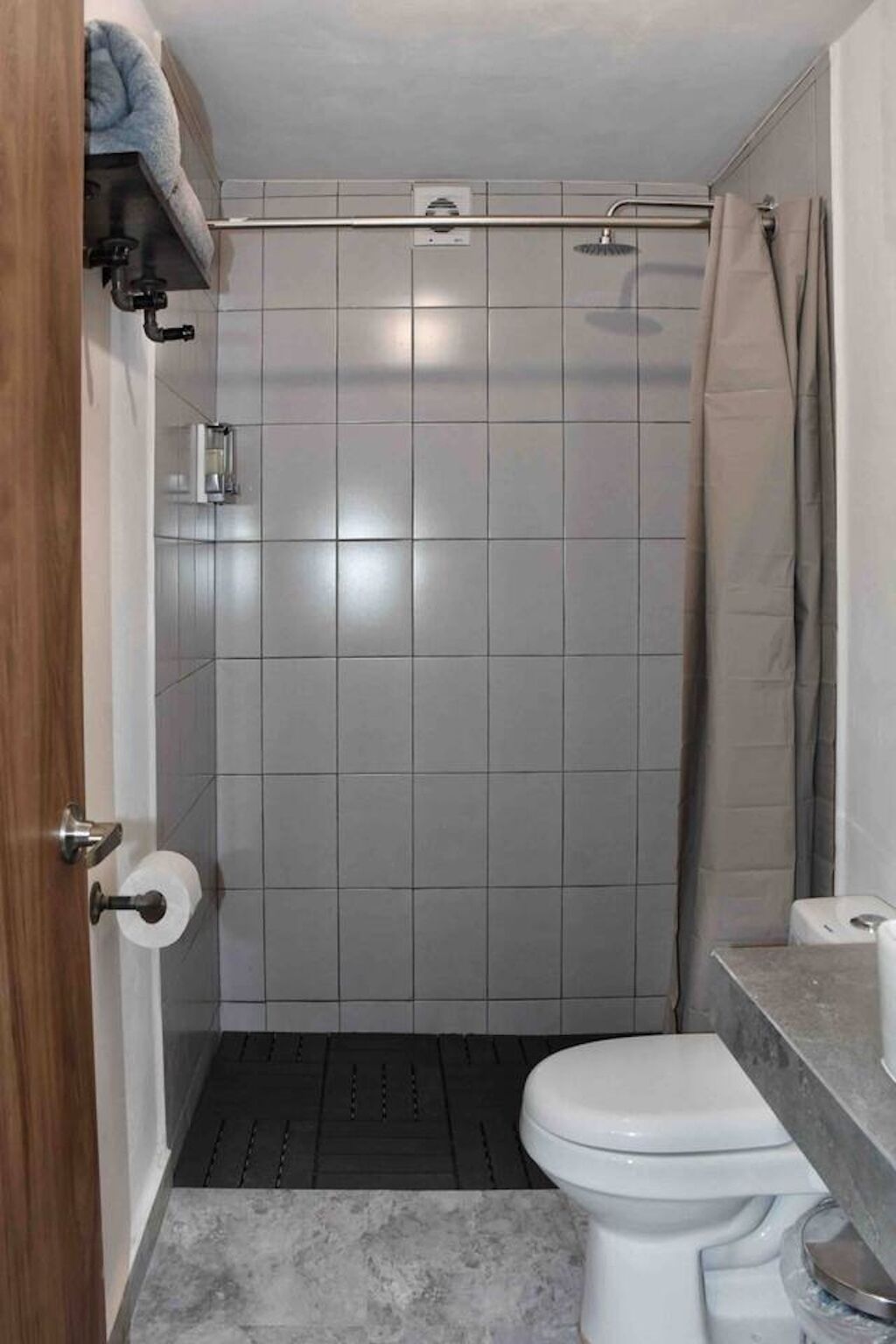 A bathroom with a shower, toilet, and a towel rack.