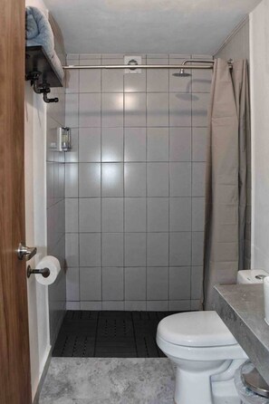 Een douche, handdoeken, zeep, toiletpapier