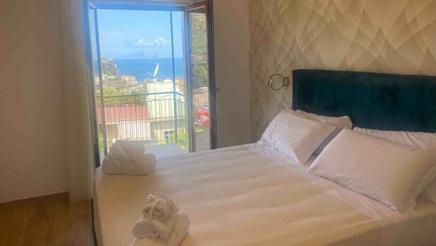 A hotel room with a bed, a view of the sea, and a balcony. - SORRENTO POSITANO AMALFI COAST "I VELIERI SUNSET SUITE" (VICO EQUENSE)