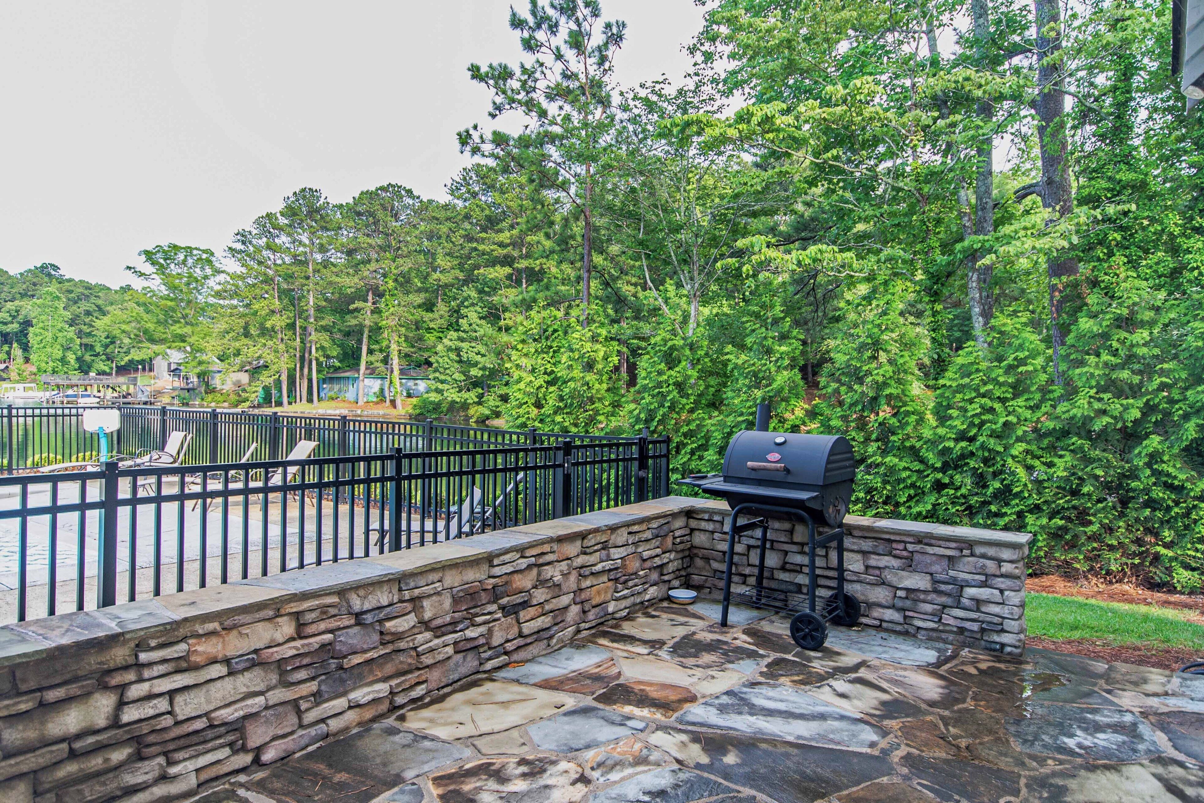 An outdoor patio with stone flooring, a grill, and a seating area.
