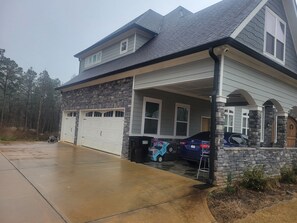 A two-story house with a garage, a covered porch, and a driveway. - Spacious 9-bedroom house in lovely Locust Grove with AC (Locust Grove)