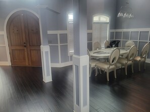 A dining area with a round table and chairs, a wooden door, and a window with blinds. - Spacious 9-bedroom house in lovely Locust Grove with AC (Locust Grove)