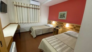 Une chambre d’hôtel avec deux lits, un bureau, une chaise, un climatiseur et un téléviseur.