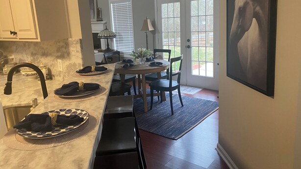 A kitchen with a marble countertop, a sink, and a dining area with a table and chairs. There is a window with blinds and a door leading outside. - 4 bedroom beautifully furnished home on over an acre. Close to 1-85 and Athens.  (Commerce)