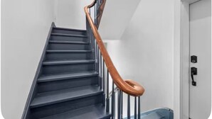 Eine Treppe mit dunklen Stufen und einem hölzernen Geländer.