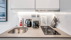 A modern kitchen with a stainless steel sink, a kettle, a toaster, and a knife block. - The Cosy Luxe (Slough)