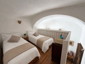 Ein Schlafzimmer mit zwei Betten, einem Holzschrank, einem kleinen Tisch und einer Heizung.