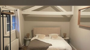 A bedroom with a bed, bedside tables, a bench, a radiator, and a window. - Charming house in the heart of the Lot (Gourdon)