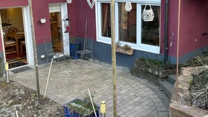 Een gebouw met een houten pergola, een bord waarop "Einklang Eingang" staat, en een raam met een hangende lantaarn.