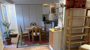Een ruimtelijk ingerichte leefruimte met een kitchenette, een eethoek en een klein keukentje.