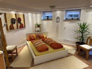 A modern bedroom with a large bed, two windows, a potted plant, and artwork on the walls. - "In harmony" vacation apartment (Buchen)