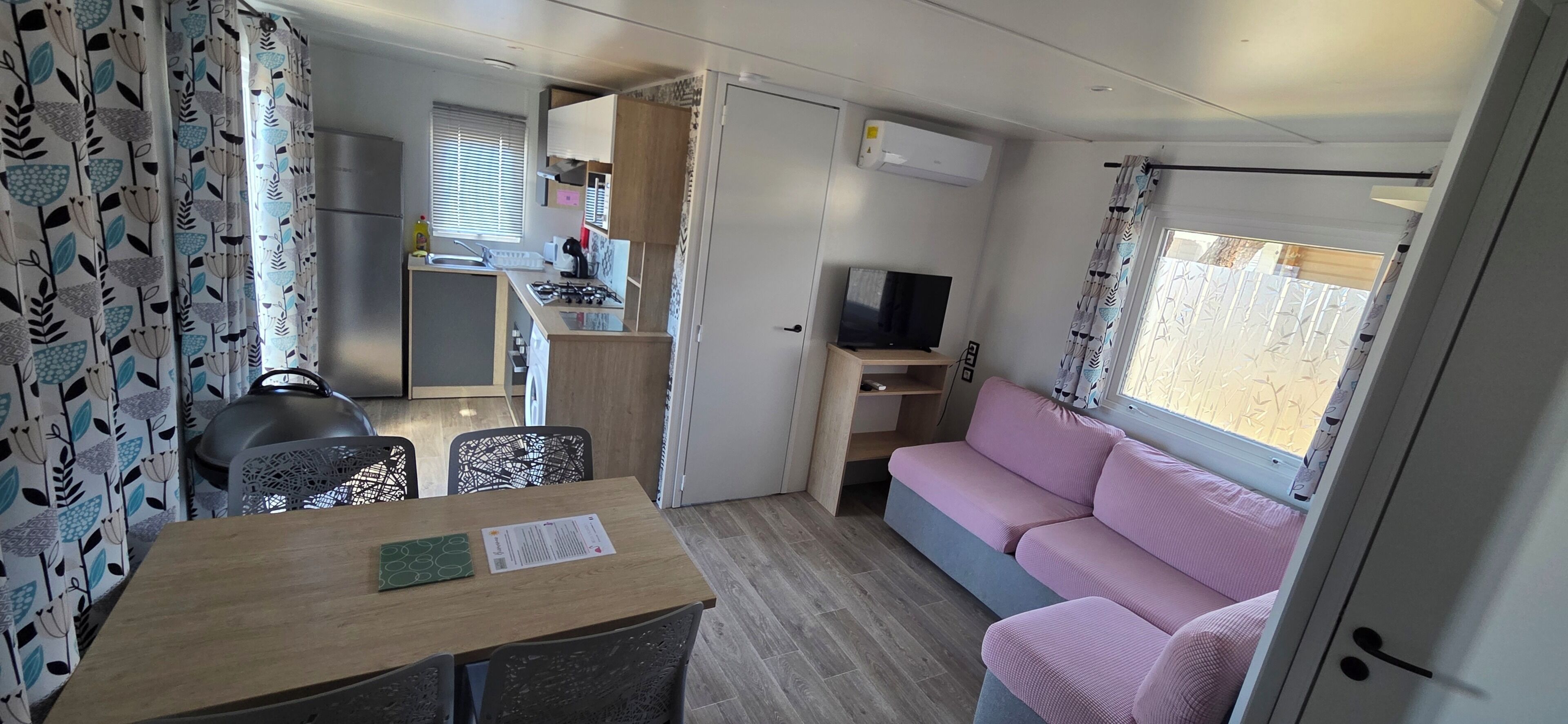 A compact living space with a kitchenette, a dining area, a sofa, and a TV.