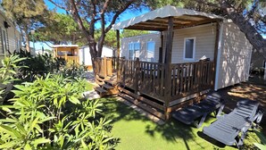 En campingvogn med træterrasse, overdækket veranda og et lille vindue.