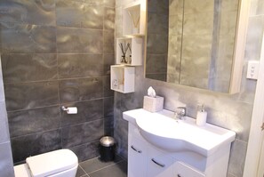 Et badeværelse med tapet, en hvid vask, et spejl og et toilet.