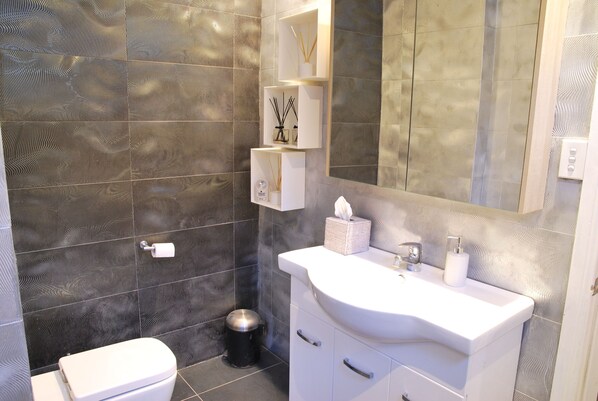 Un baño con pared estampada, un lavabo blanco, un espejo y un inodoro.