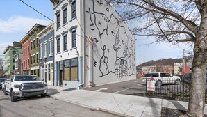 Una calle con un mural en un edificio, coches aparcados y una acera.