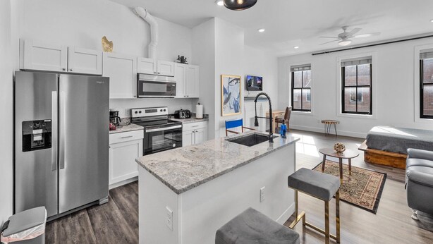 Una cocina moderna con una isla central, electrodomésticos de acero inoxidable y una decoración en tonos blancos.