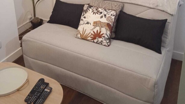 Ein gemütliches Wohnzimmer mit einer Couch, einem kleinen Tisch und einer Topfpflanze.