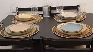 Ein Esstisch mit Geschirr, Gläsern und einer Karaffe, umgeben von Stühlen.