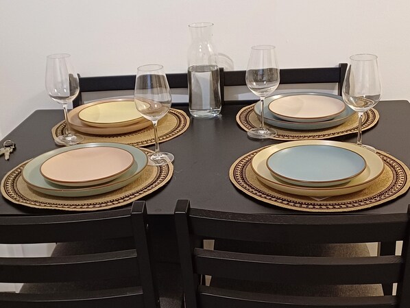 A dining table set with plates, glasses, and a pitcher, surrounded by chairs. - Apartment in the center of Paris, 1 min from the metro (Paris)