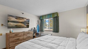 A bedroom with a large bed, a wooden dresser, a television, and a window with curtains. - King Room Retreat in Nisswa – Indoor Pool, Sauna & Near Gull Lake (Nisswa)