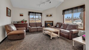 A living room with leather sofas, a fireplace, and large windows with a view of the outside. - King Room Retreat in Nisswa – Indoor Pool, Sauna & Near Gull Lake (Nisswa)