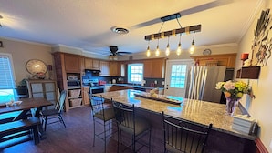 A kitchen with a central island, wooden cabinets, a microwave, and a refrigerator. - 3-bedroom home with great  backyard  & pool with a  private and peacful setting (Spring Hill)