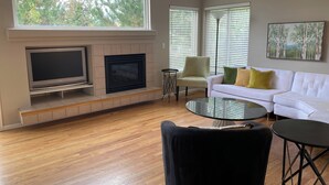 Uma sala de estar com lareira, televisão, sofá e mesa de centro.
