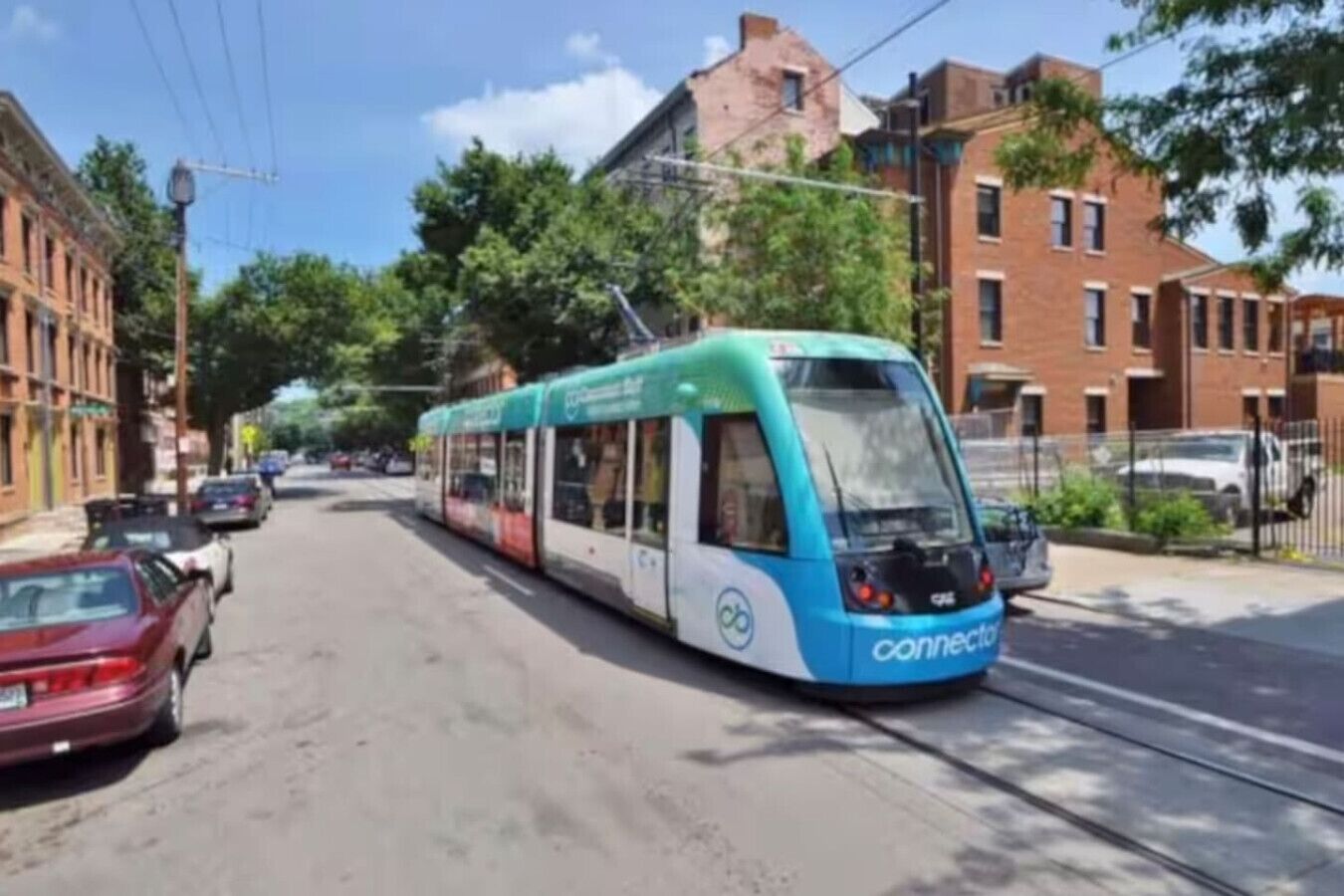 Un tranvía moderno en una calle urbana, con edificios y automóviles estacionados.