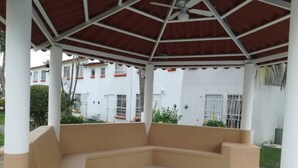 A covered outdoor seating area with a curved bench, white pillars, and a red roof. - 22 - Casa en Acapulco Zona Diamante Joyas del Marques - Alojamiento entero (Acapulco)