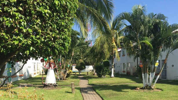 A pathway leading through a well-maintained garden with palm trees and a white building in the background. - 22 - Casa en Acapulco Zona Diamante Joyas del Marques - Alojamiento entero (Acapulco)