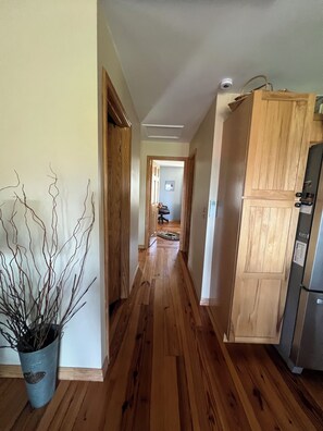 A hallway with wooden flooring, a potted plant, and a refrigerator. - Lakeside cottage in the ADK with LAKE and MTN views w/boat launch and amenities! (Westport)