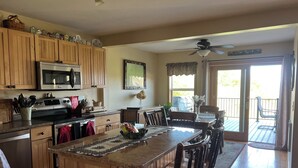 A kitchen with wooden cabinets, a central island, and a dining area with chairs. - Lakeside cottage with lake and mountain views, boat launch access & amenities. (Westport)