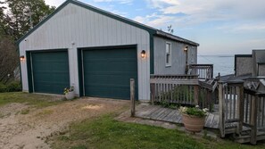 Eine Doppelgarage, an ein Haus angebaut, mit einer Holzterrasse und Blick auf das Wasser.