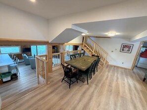 Ein geräumiges Loft mit Essbereich, einer Treppe und Blick ins Freie.