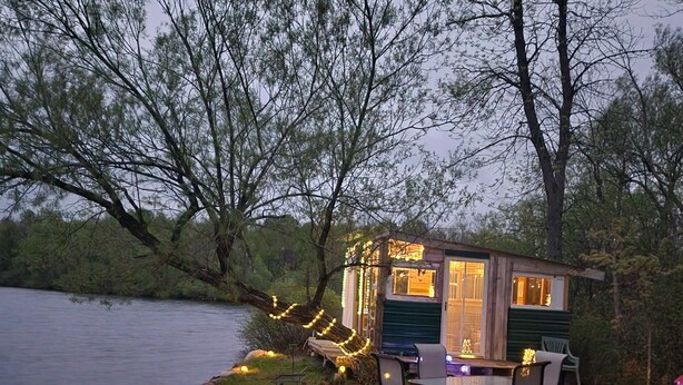 A lakeside cabin with a patio, outdoor seating, and string lights. - Lakeside oasis Apt with water access and views.
There is a She shed on the beach (Norwood)