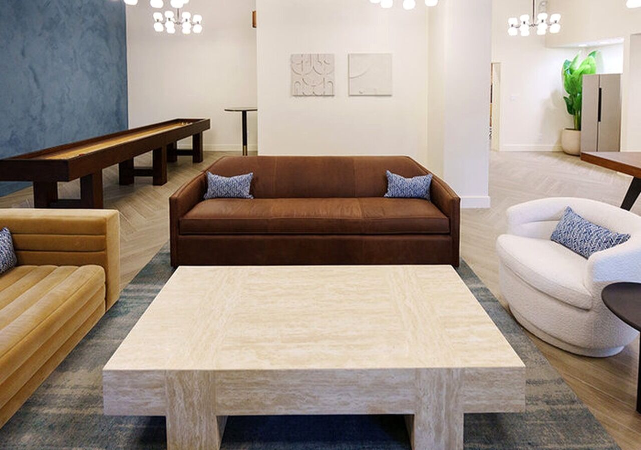 A modern living room with a brown sofa, a white armchair, and a wooden coffee table.