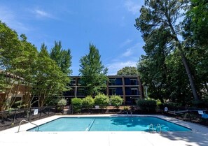 Une piscine entourée d’arbres et un bâtiment au design moderne.