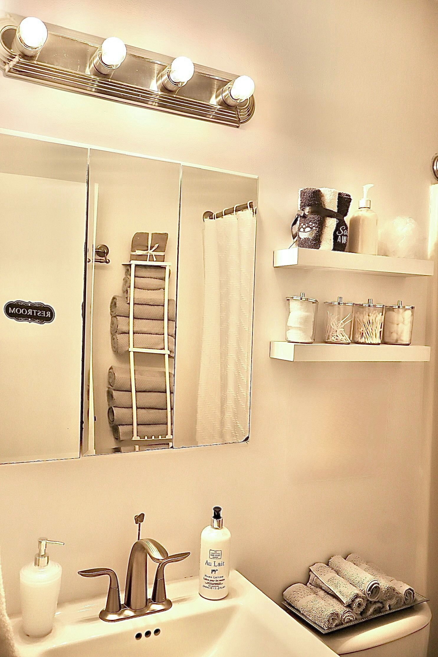 Une salle de bain équipée d’un meuble-lavabo, d’un miroir, d’un porte-serviettes et d’étagères contenant des articles de toilette.