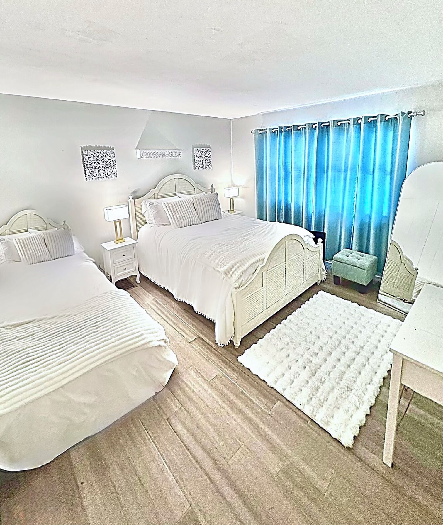 Une chambre avec deux lits, une table de chevet, une lampe, une chaise et une fenêtre avec des rideaux.