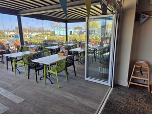 An outdoor dining area with tables and chairs, a glass door entrance, and a view of the surrounding area. - Skegness holiday park, Bella-Mays holiday hideaway. Sleeps 8! Pet friendly. (Skegness)