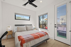 A bedroom with a bed, a window, a ceiling fan, and a view of the outside. - Downtown - Pool + Family + Deck + FirePit + Pets (Austin)