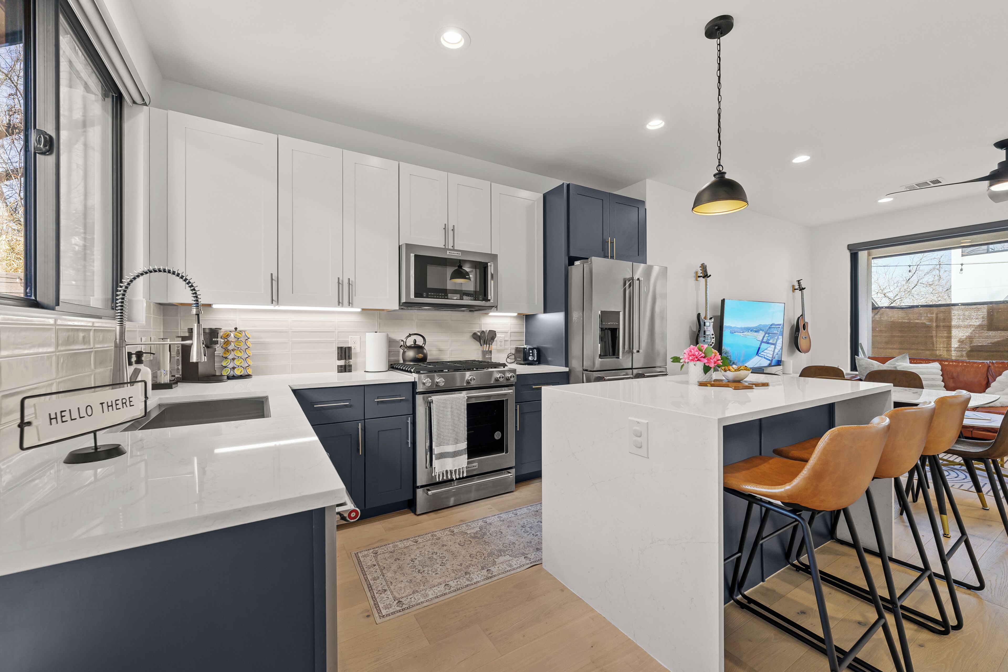 A modern kitchen with white cabinetry, stainless steel appliances, and a central island with bar stools.