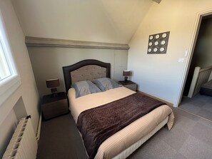 Een slaapkamer met een bed, nachtkastjes, een wandklok en een radiator.