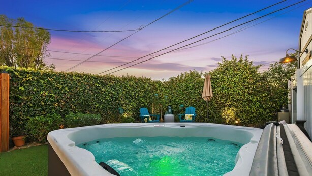 Ein Whirlpool im Hinterhof mit einer Hecke, Stühlen und einem Lampenpfosten.