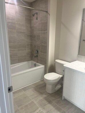 A bathroom with a bathtub, toilet, and a shower area. - In Beautiful Townhome / MasterBedroom (Calgary)